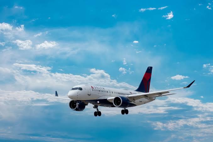 Commercial passenger airplane flying high through blue skies and white clouds, illustrating the complex landscape of federal travel regulations and whether medical marijuana is allowed on planes.